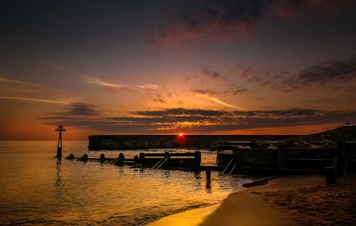 Breakwater and Pier on Sea Shore at Sunset