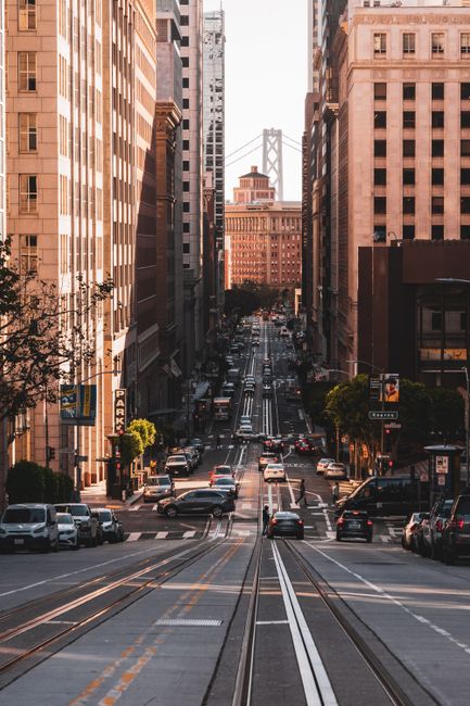 Iconic San Francisco street scene featuring the Bay Bridge and urban cityscape at sunset.