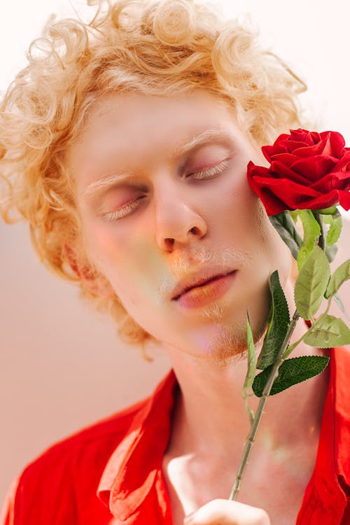 赤いバラの花を持っている赤い襟付きシャツを着ている男