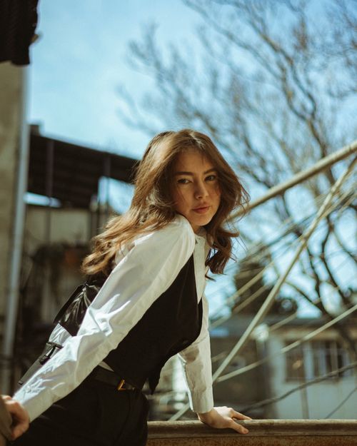 Free Woman posing stylishly outdoors, wearing a chic blouse and waistcoat, under clear skies. Stock Photo