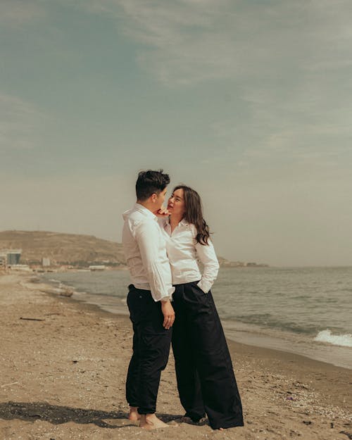 A couple standing on the beach in front of the ocean