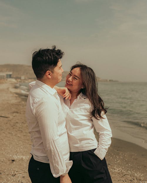 A couple standing on the beach in front of the ocean