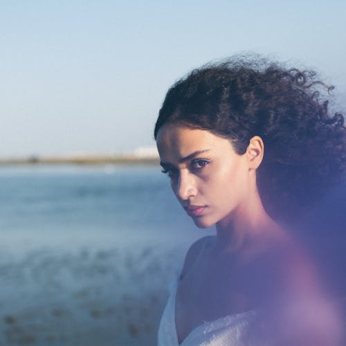 A woman with curly hair standing near the water