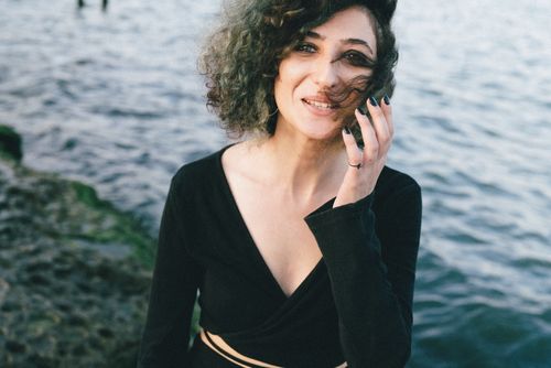 Free Portrait of a smiling woman with curly hair enjoying the sea breeze. Stock Photo