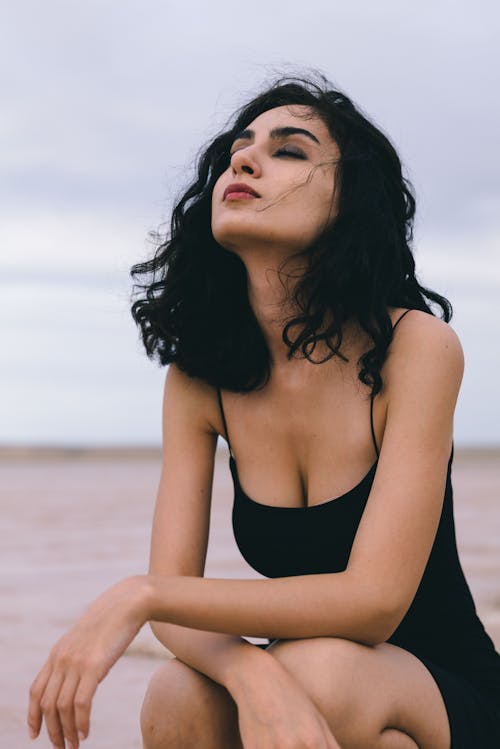 Woman with Black Hair Squatting with Eyes Closed