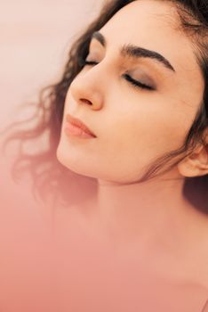 Peaceful portrait of a young woman with closed eyes in soft lighting, exuding tranquility.
