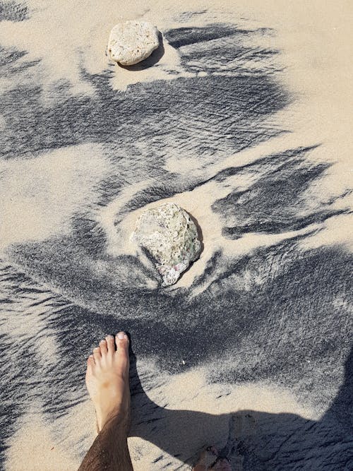 Person's Foot on Sand Near Rock