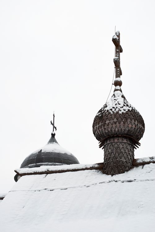 Free Snow-covered wooden church domes with intricate crosses under an overcast sky. Stock Photo