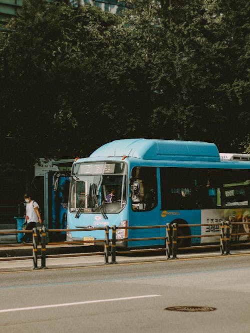 A blue bus is driving down a street