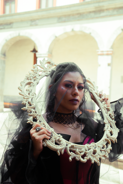 Free A gothic woman poses with an ornate frame in a historic courtyard in Mexico City, Mexico. Stock Photo