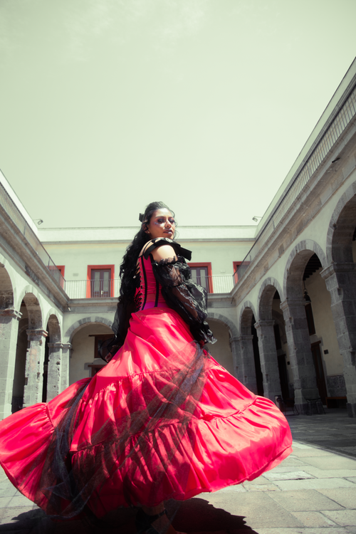 Free An elegant woman twirls in a vibrant red dress, creating a dynamic and festive scene within a historic Mexican courtyard. Stock Photo