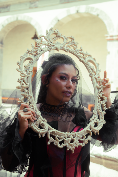 Free A woman in a gothic red dress poses with an ornate mirror, creating a vintage and mysterious vibe. Stock Photo