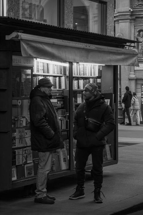 2 men talking next to bookstand in center Milan