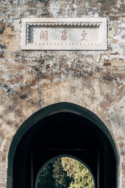 A man walking through an archway with chinese writing on it