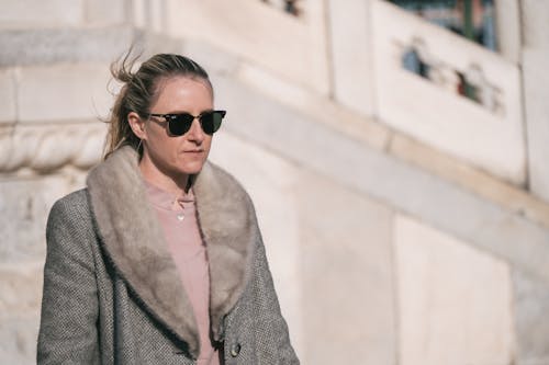 A woman in sunglasses and a fur coat walking down a street