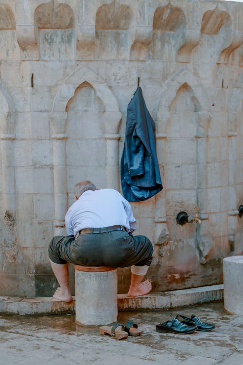 Elderly Man Sitting in Front of a Fountain 