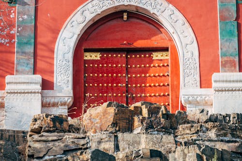 A red door with a red door and a rock wall