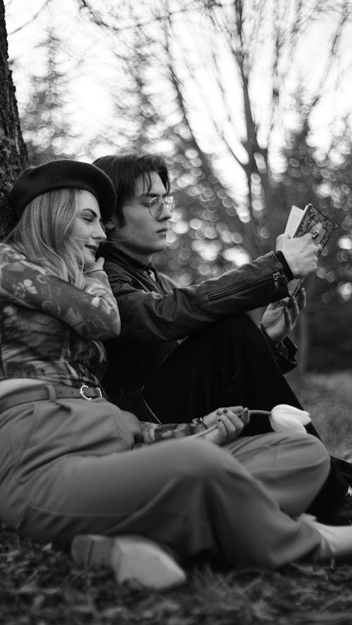 A black and white photo of a couple sitting under a tree