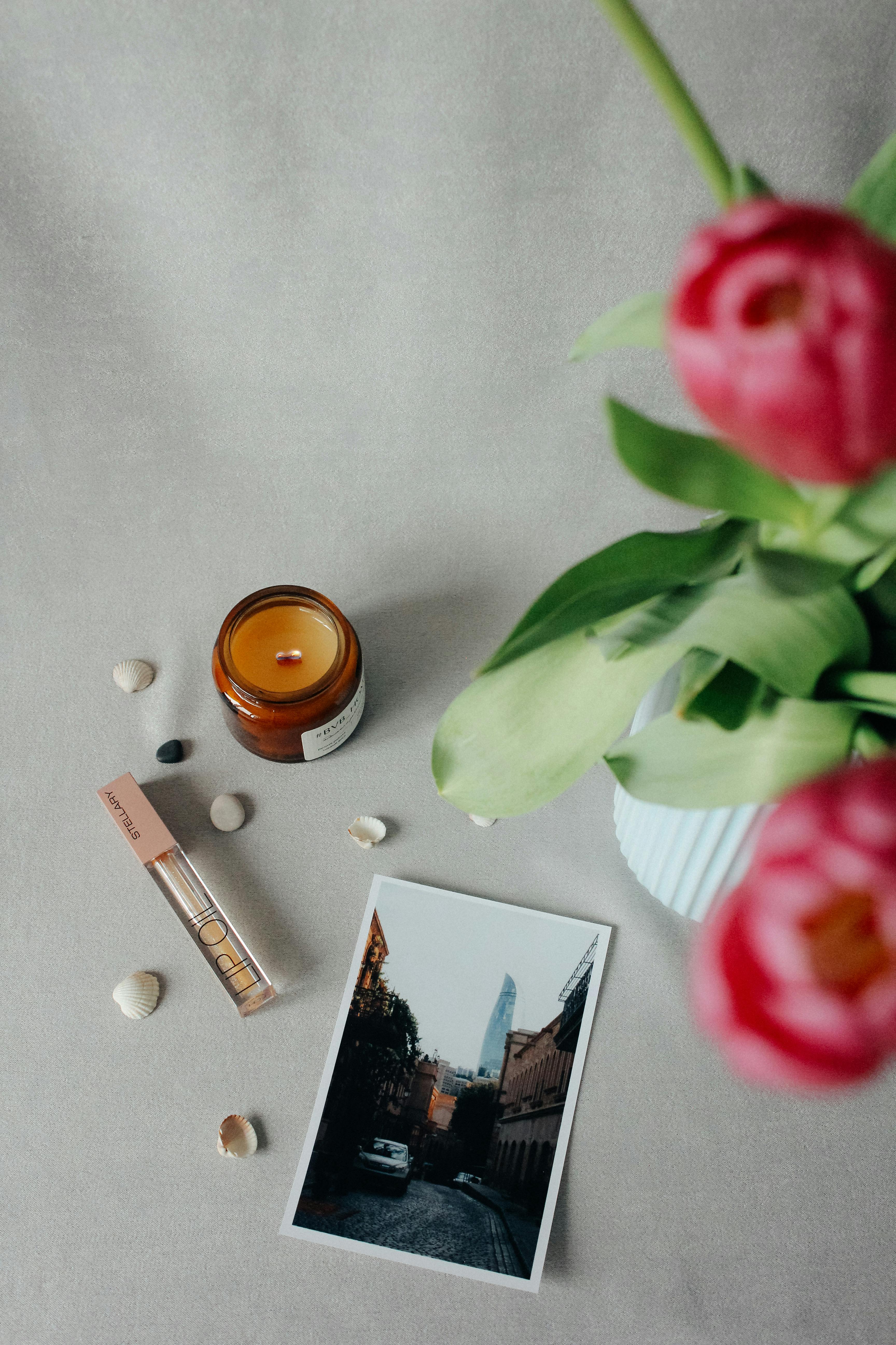 A cozy flat lay with a candle, flowers, and a photo capturing urban street scenery.