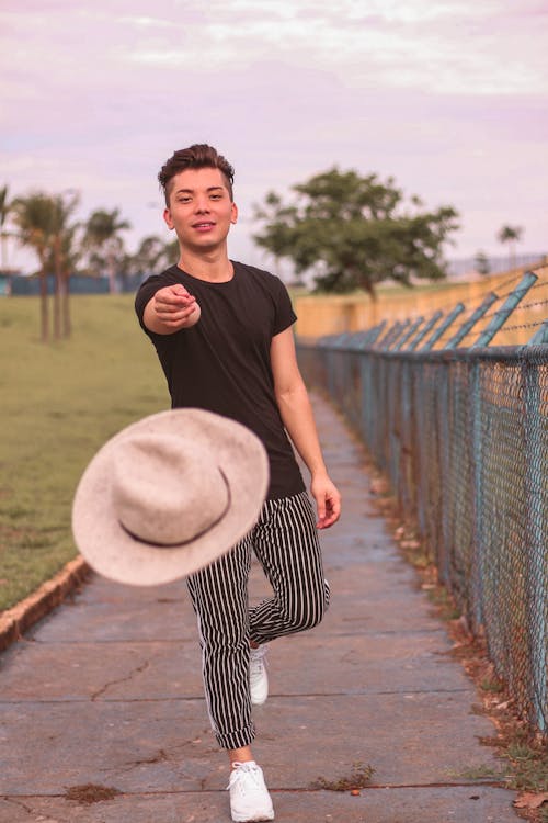 無料 帽子を投げるフェンスの横に立っている男 写真素材