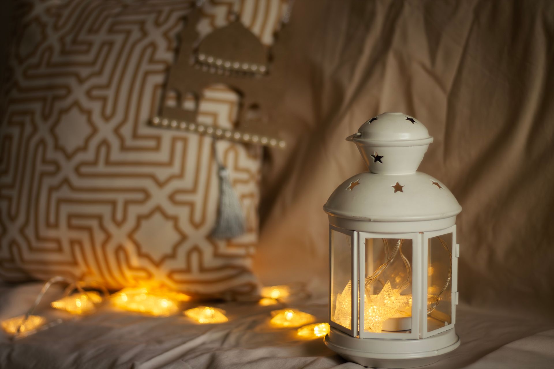 A decorative lantern gently illuminating a cozy setting with soft golden star lights, creating a warm indoor ambiance.