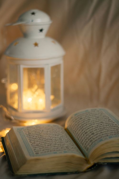 Free Open Quran with a glowing lantern, creating a serene and spiritual ambiance. Stock Photo