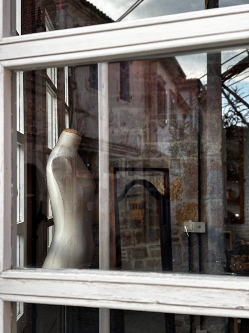 A mannequin is reflected in a window