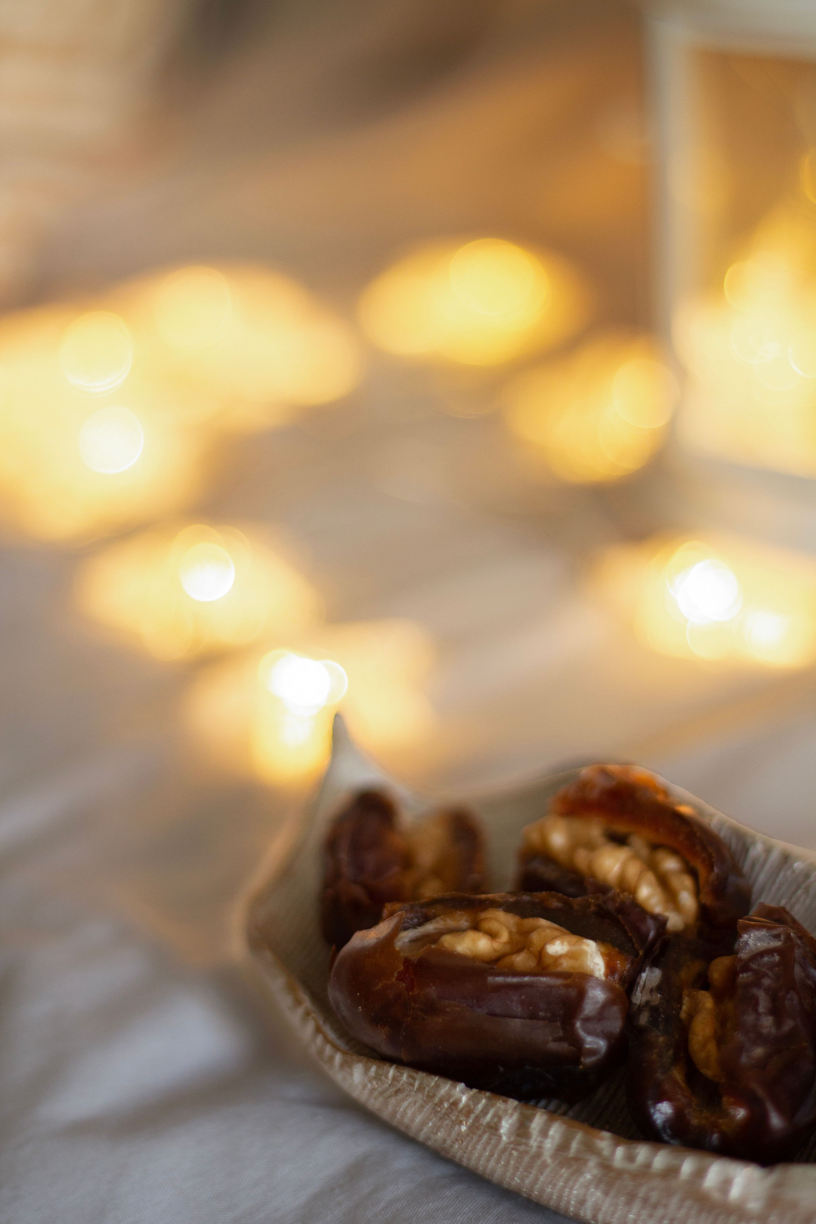 Soft focus on a bowl of stuffed dates with glowing lantern lights, perfect for Ramadan.