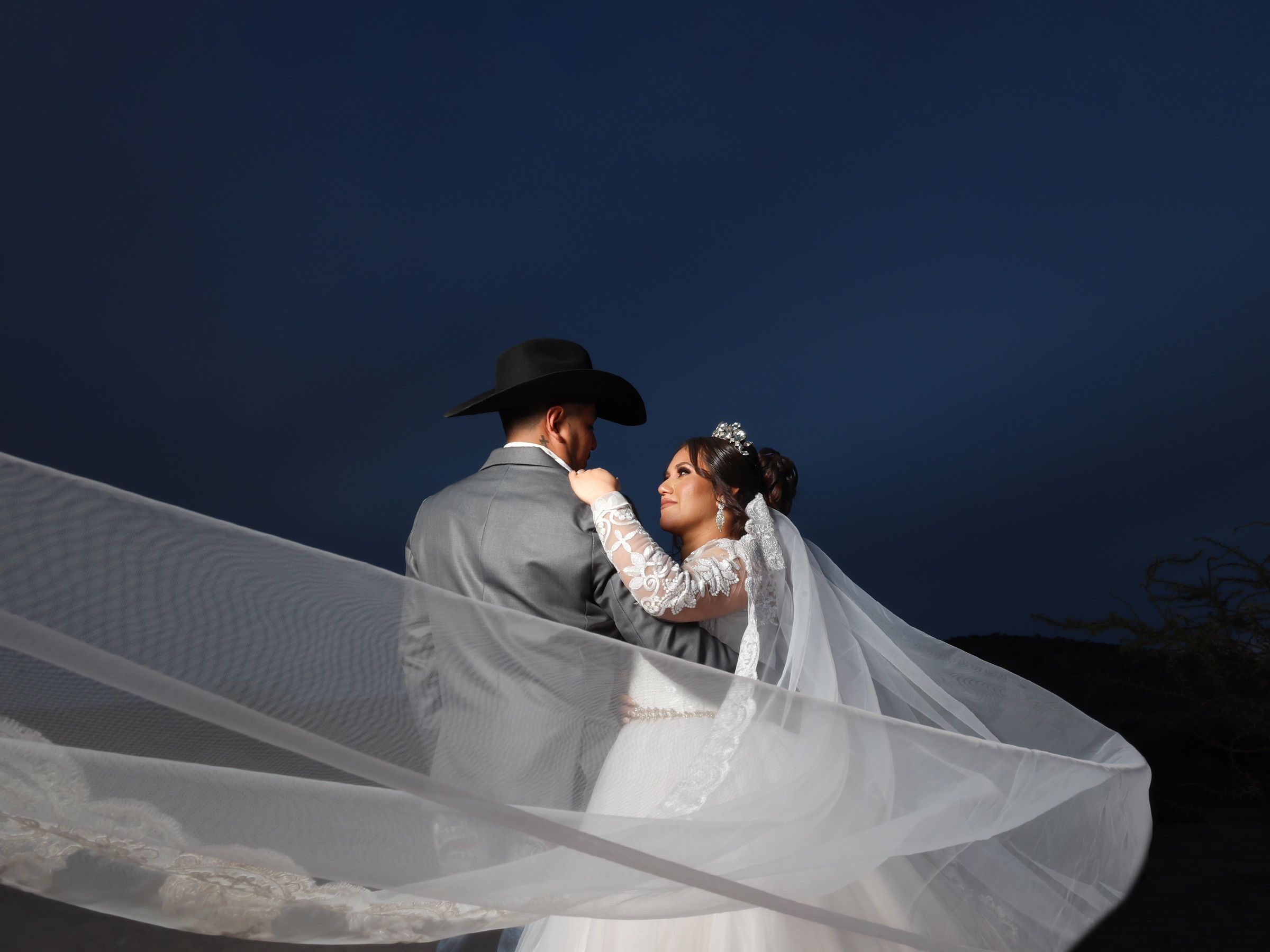 A newlywed couple embraces under the night sky in San Felipe, México.