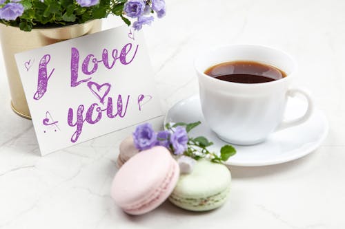 White Ceramic Teacup on Saucer next to Love Message