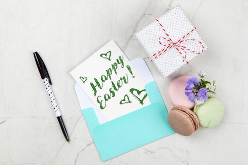Free Flat lay of Easter greeting card with gift box, macarons, flowers, and pen on marble background. Stock Photo