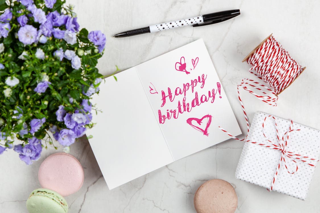 Free Happy Birthday Card Beside Flower, Thread, Box, and Macaroons Stock Photo