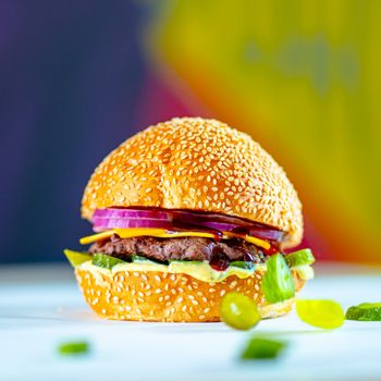 Delicious gourmet cheeseburger with vibrant ingredients and a sesame seed bun.