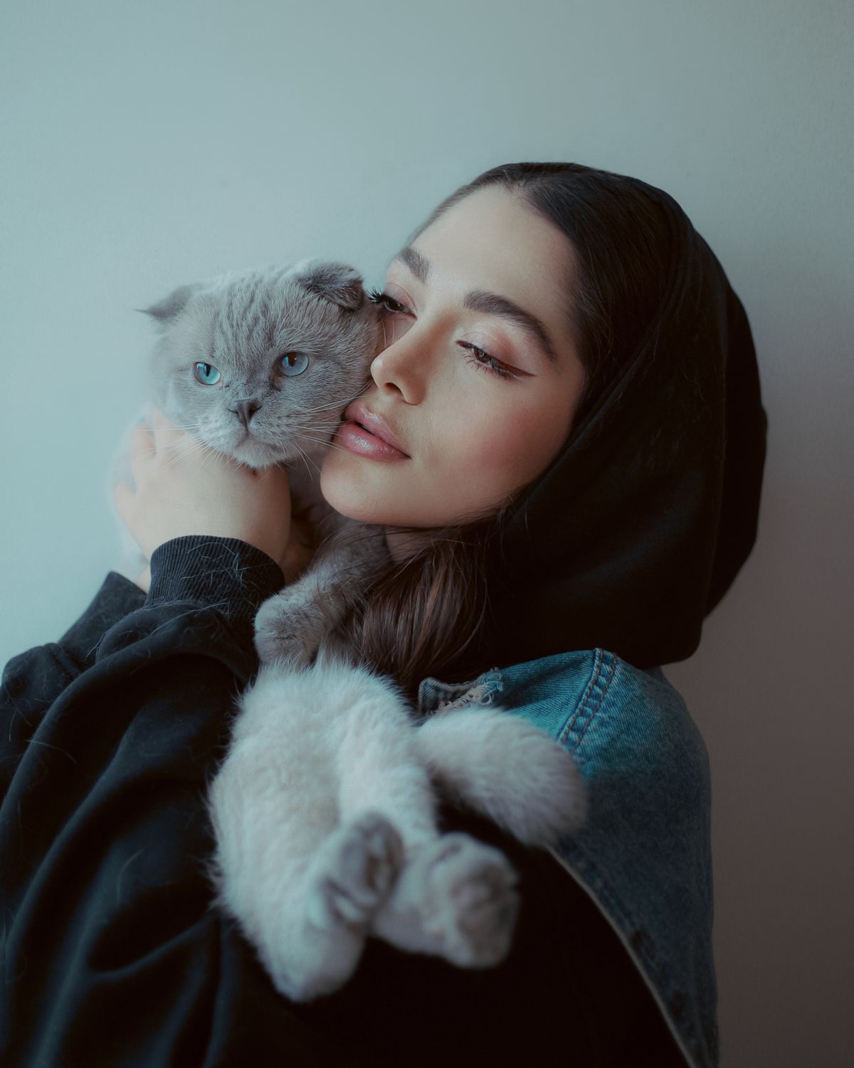 Woman affectionately cuddling a fluffy cat at home, with their faces fully visible