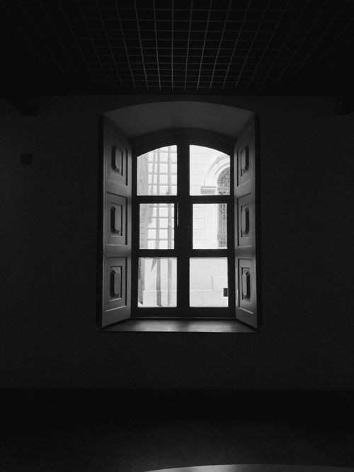 Free Stylish black and white photo of an open window in a dark room, offering a glimpse outside. Stock Photo