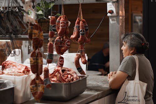 A woman looking at meat hanging on a rack