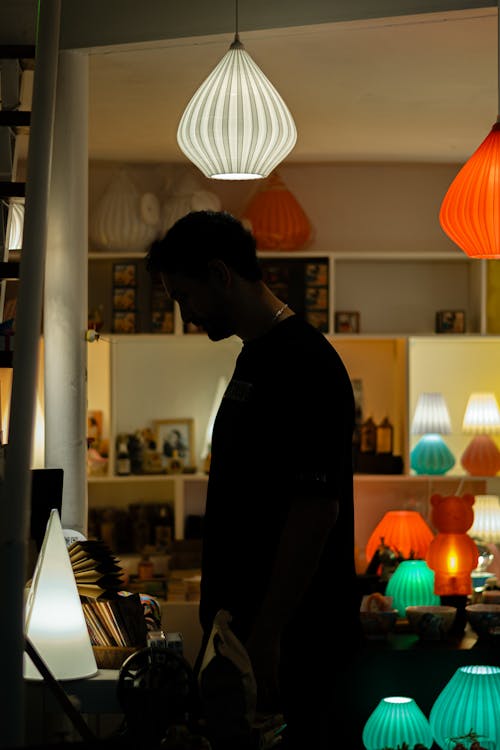 A man standing in a room with lamps hanging from the ceiling