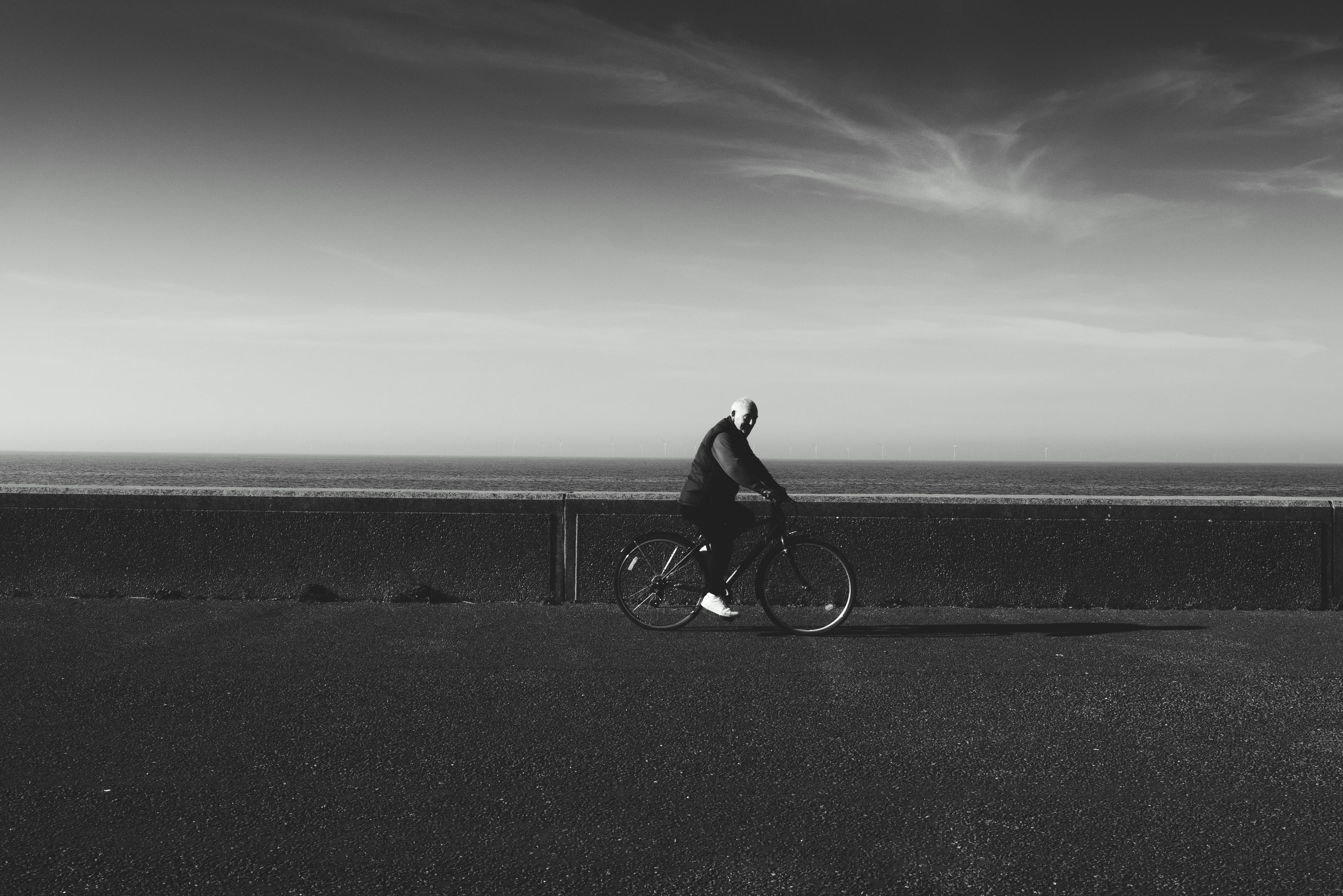 一张黑白照片中，一个人在海边骑自行车，展现了极简主义与孤独感