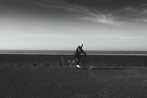 Grayscale Photo of Man Riding Bicycle