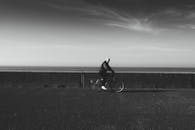 一张黑白照片中，一个人在海边骑自行车，展现了极简主义与孤独感