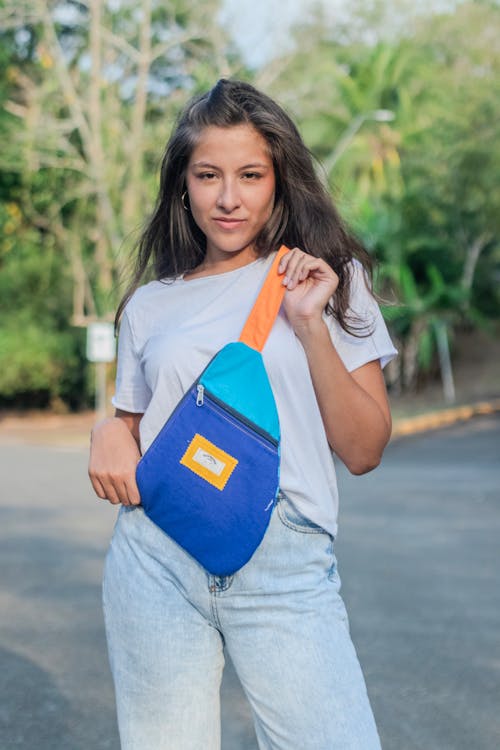 A young woman holding a blue and orange fanny bag