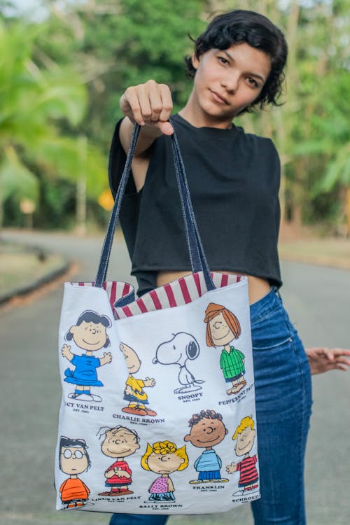 A woman holding a tote bag with cartoon characters on it