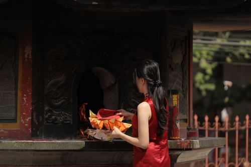 Free A woman in a red dress participates in a traditional ritual at a temple, exuding elegance and cultural significance. Stock Photo