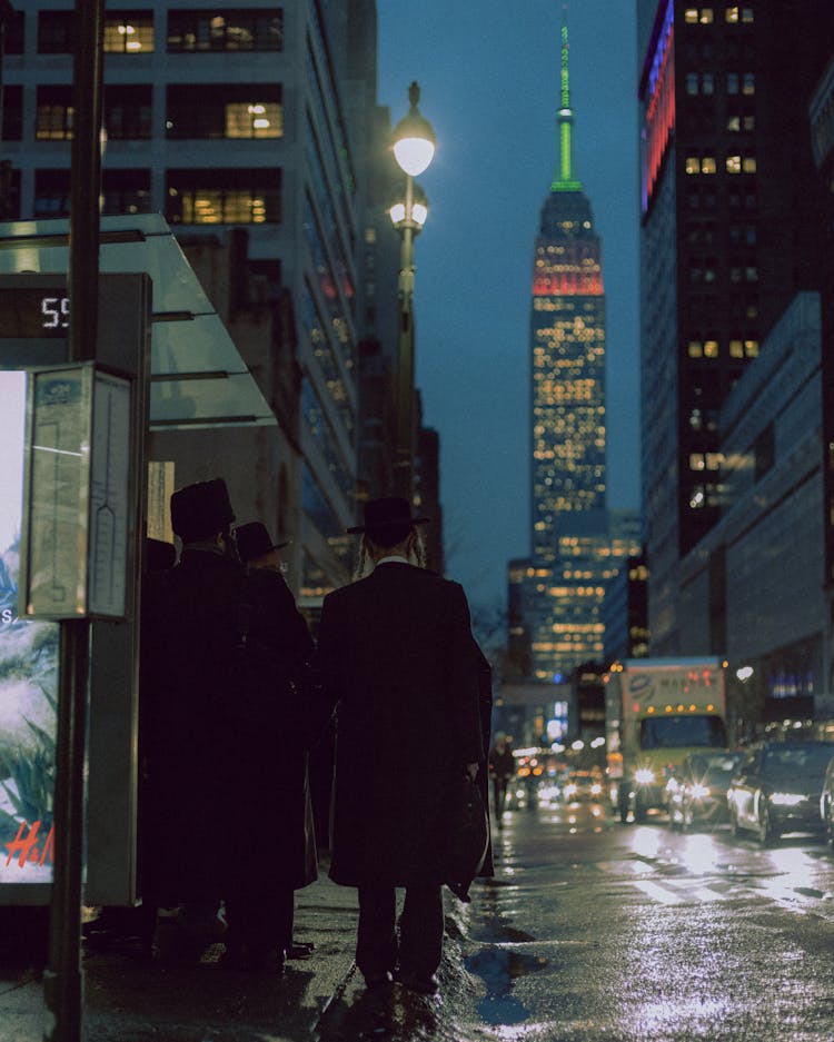 Empire State Building Behind People Standing On Bus Stop