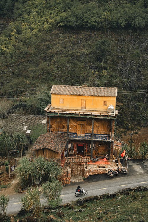 A house on a hillside with a motorcycle on the road