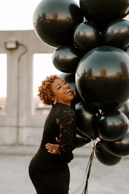 Smiling Woman Holding Black Balloons 