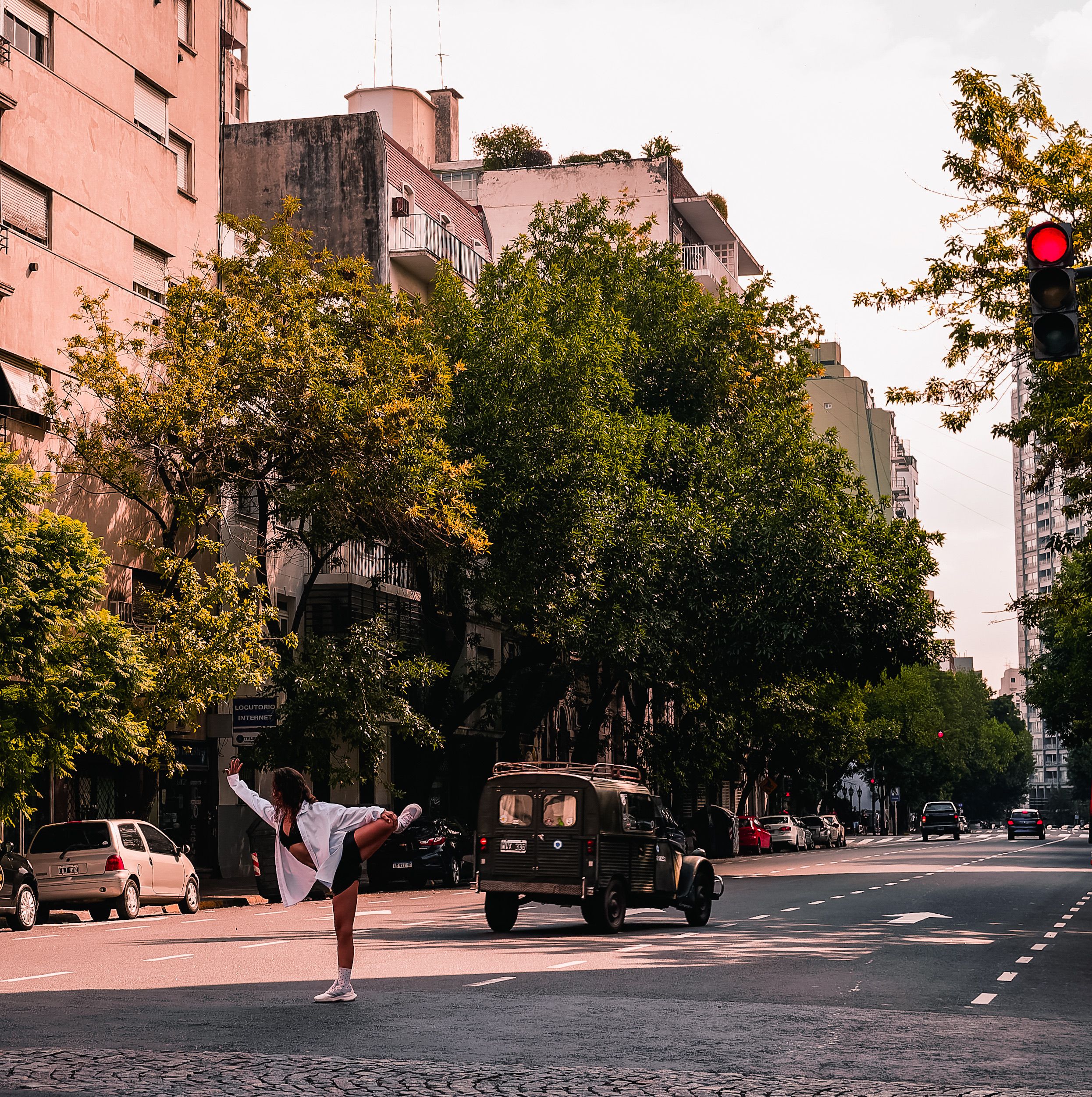 Woman doing a stretching pose on a city street. Urban scenery with trees and buildings.