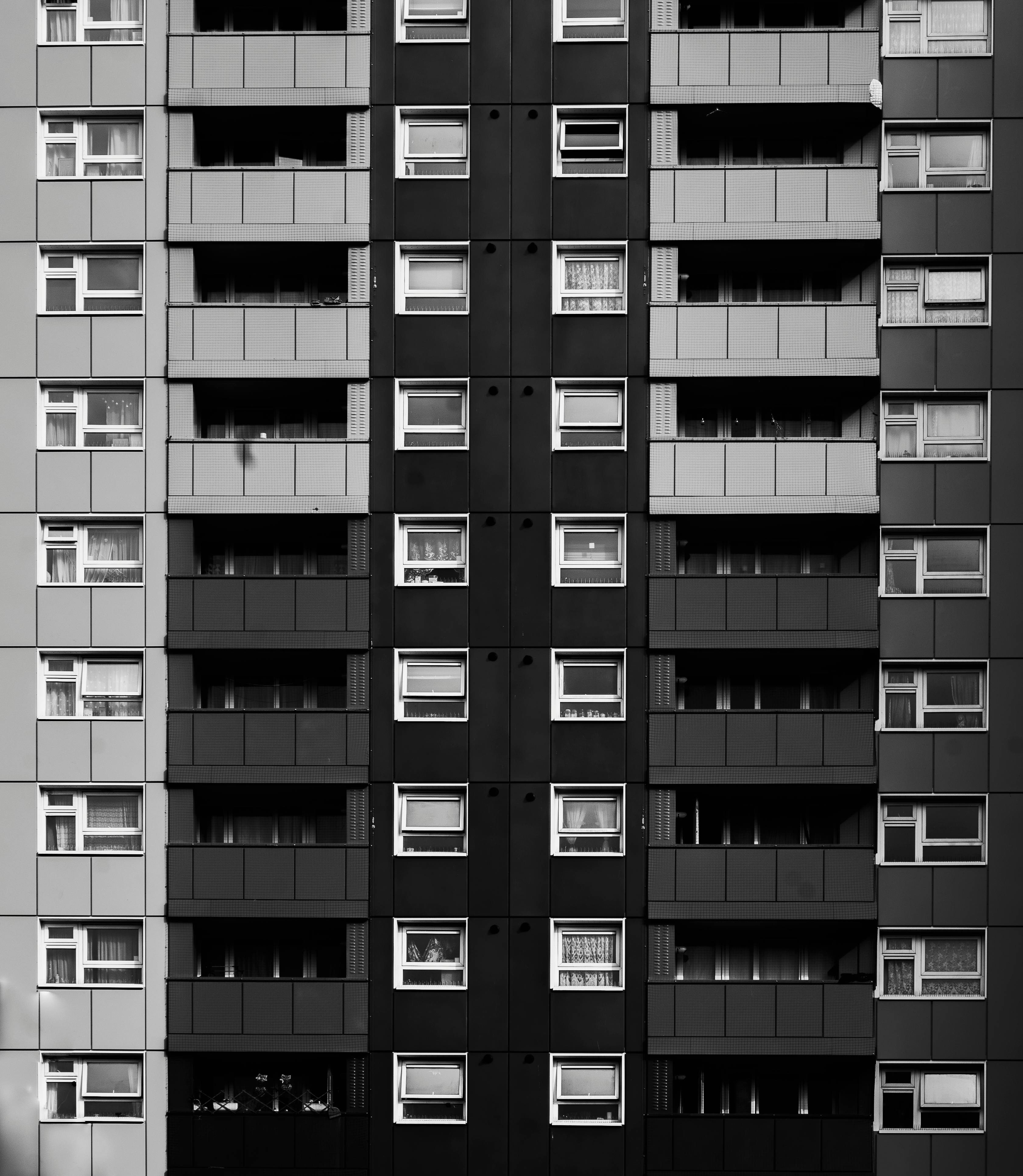 Black and white image of a high-rise apartment building facade with aligned windows.