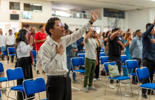 A man in a white shirt is raising his hands