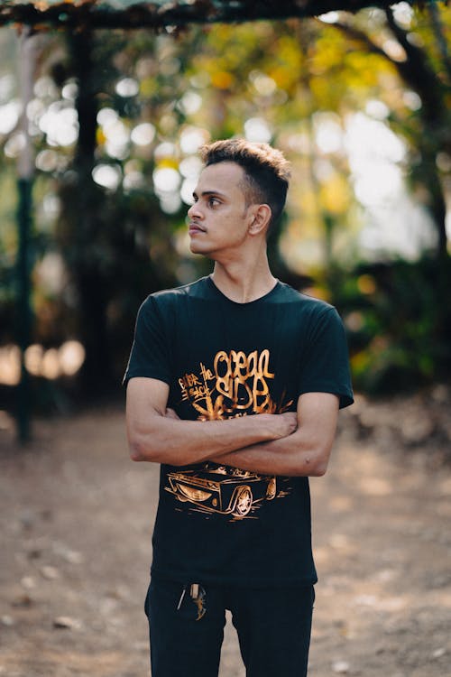 A man standing in the woods wearing a black shirt